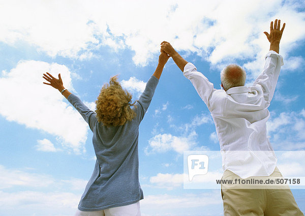 Älteres Paar mit erhobenen Armen  Händchen haltend  Rückansicht  Tiefblick
