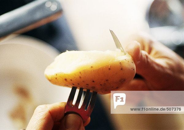 Nahaufnahme der Hände beim Schälen einer Kartoffel