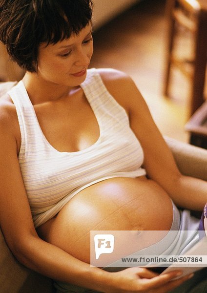 Pregnant woman reading in armchair  high angle view