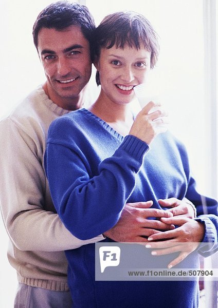 Man with arms around pregnant woman  portrait