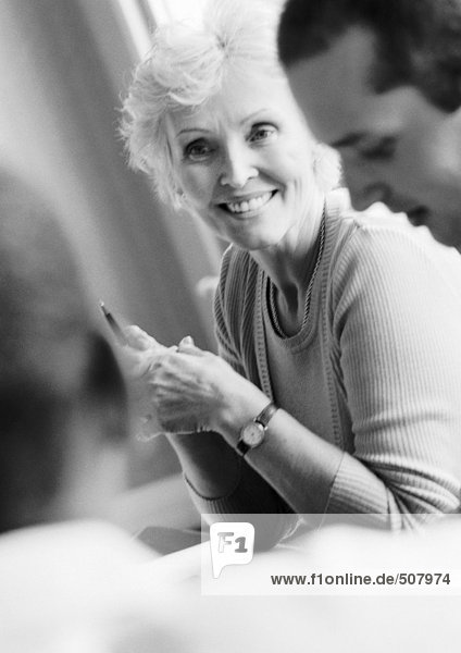 Mature businesswoman in conference  smiling  with two colleagues  B&W