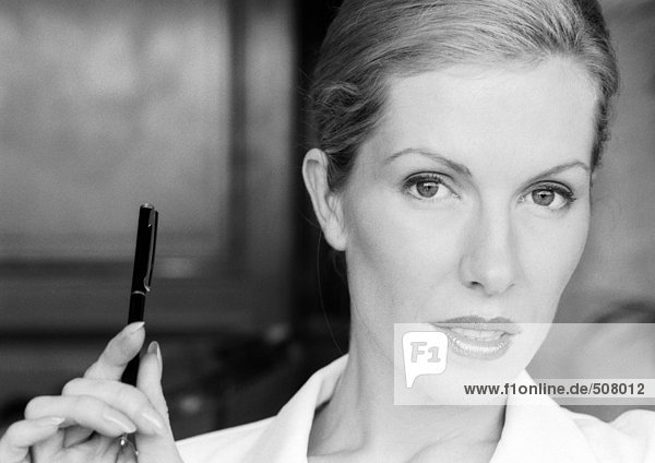 Businesswoman holding up pen  close-up portrait  B&W