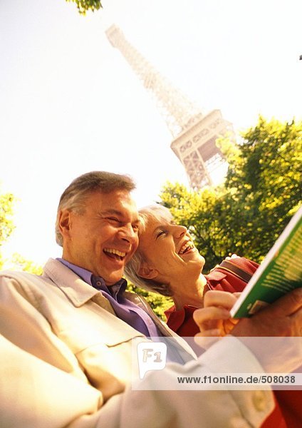Frankreich  Paris  reife Frau und Mann mit Buch und Lachen  Eiffelturm im Hintergrund