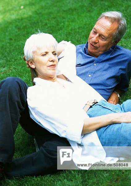 Reife Frau und Mann auf Gras liegend