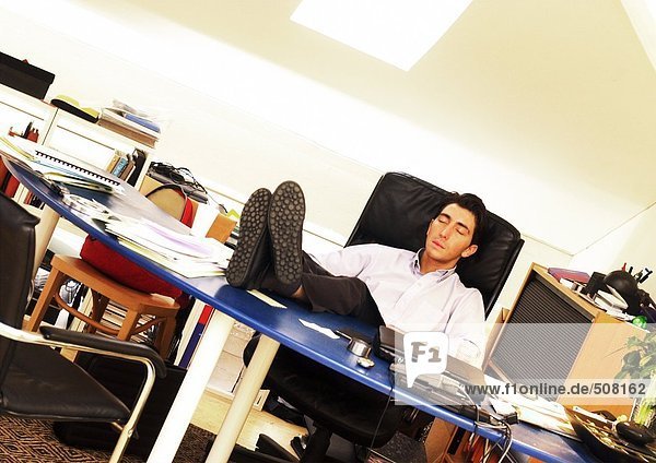Mann sitzend mit Füßen auf dem Schreibtisch  Augen geschlossen