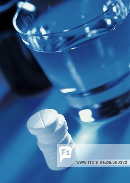 Tablettenstapel und Wasserglas