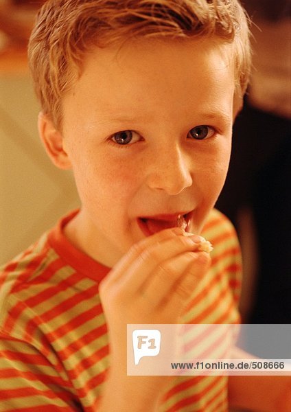 Kind beim Essen im Mund  Blick in die Kamera  Porträt