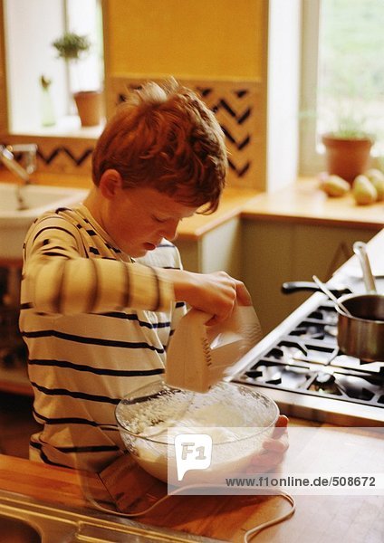 Kind in der Küche stehend  Teig mischend mit elektrischem Mischer  verschwommene Bewegung
