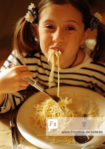 Kind isst Spaghetti,  lächelt vor der Kamera