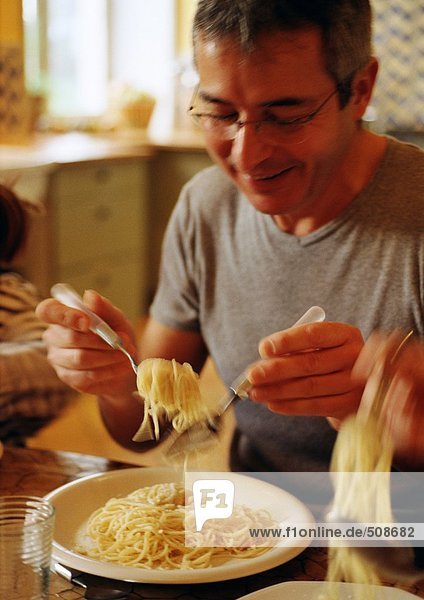 Mann isst Spaghetti mit Gabel und Löffel  verschwommene Bewegung
