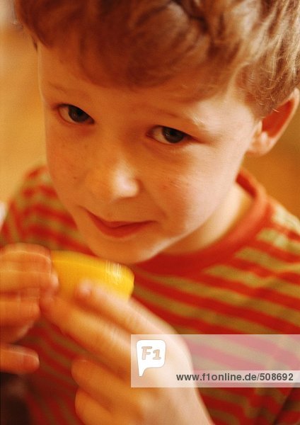 Kind hält Zitronenhälfte  Blick in die Kamera  Nahaufnahme  Portrait