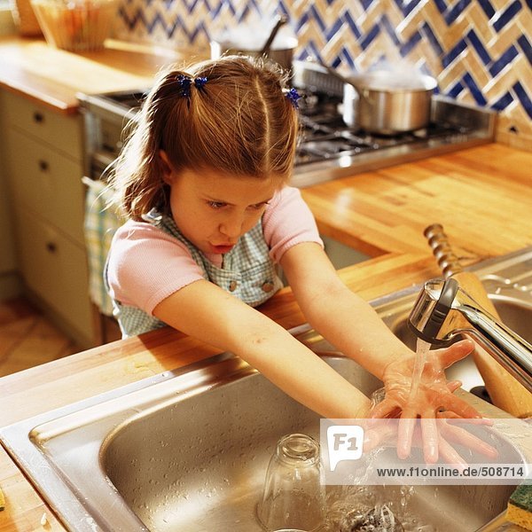 Kind hält Hände unter der Küchenarmatur