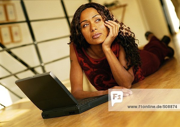 Frau auf dem Boden liegend mit Laptop-Computer