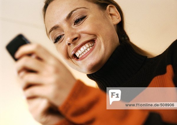 Frau lächelt mit Handy in den Händen  Blickwinkel niedrig