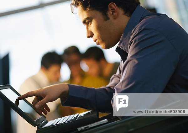 Mann schaut auf Laptop-Computer  Seitenansicht