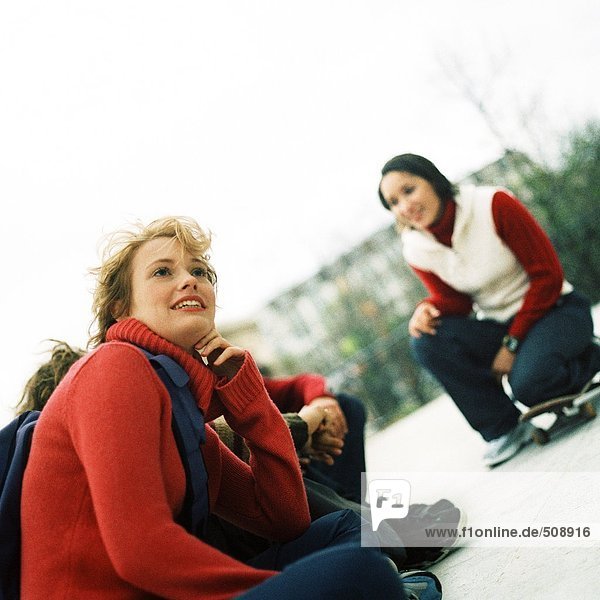 Jugendliche im Freien  einer mit Knie auf Skateboard