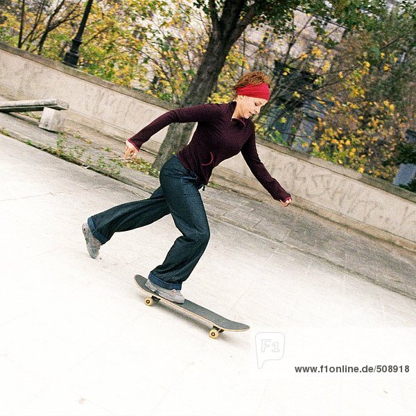Junge Frau Skateboarding  Seitenansicht