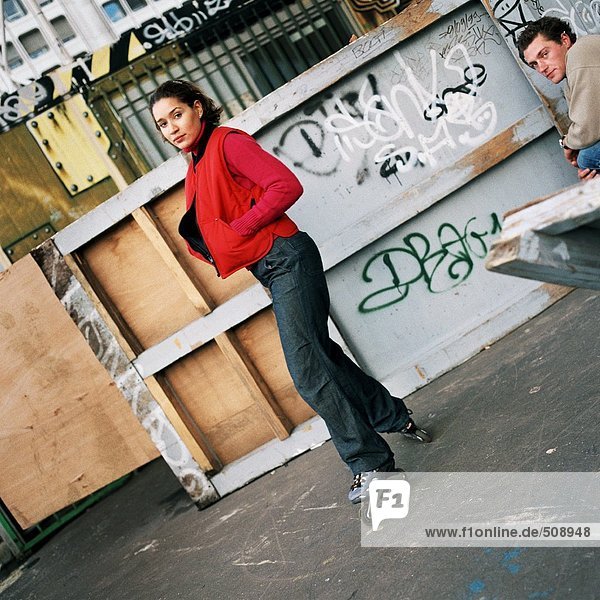 Junge Frau mit Inline-Skates  junger Mann sitzend  Portrait
