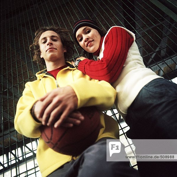Junger Mann mit Basketball  junge Frau lehnt sich auf die Schulter  Blickwinkel niedrig