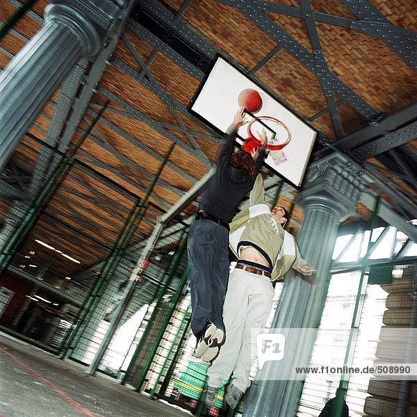 Young men in mid-air jump with basketball  blurred
