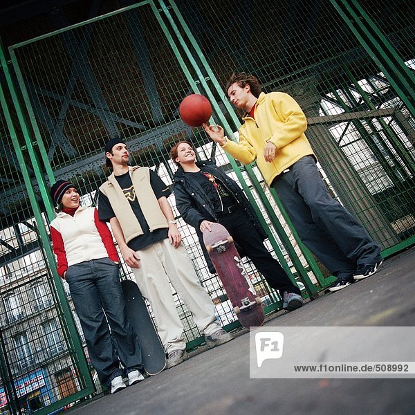 Junge Leute  die gegen den Zaun stehen  ein sich drehender Basketball