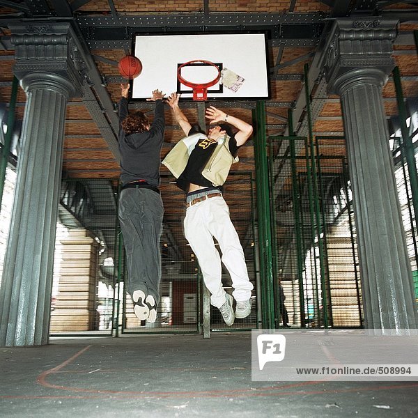 Junge Männer springen in der Luft unter dem Basketballtor  verwischt
