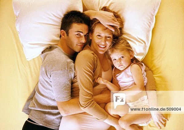 Paar und Kind auf dem Bett liegend  erhöhte Ansicht  Portrait
