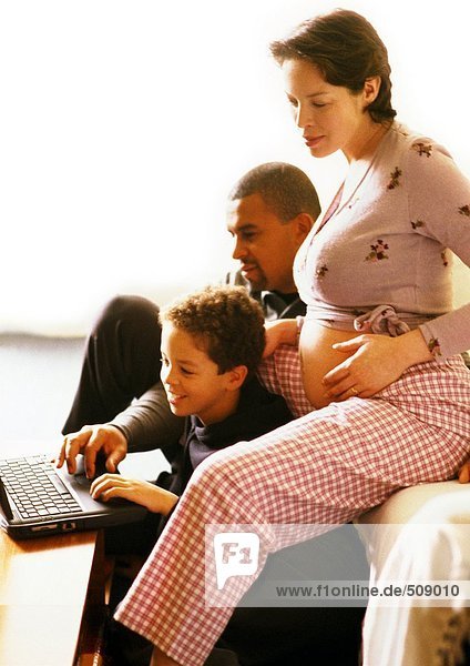 Pregnant woman sitting with man and child  child using laptop computer