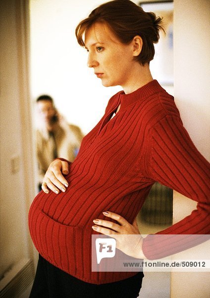 Schwangere Frau stehend mit der Hand auf dem Bauch  Seitenansicht