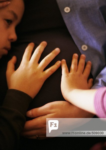 Kinder  die den schwangeren Magen der Mutter berühren  Nahaufnahme