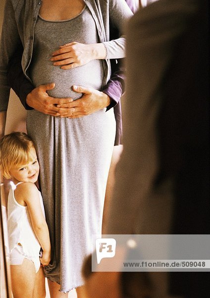 Hände auf den Bauch der Schwangeren  Kind neben der Frau stehend