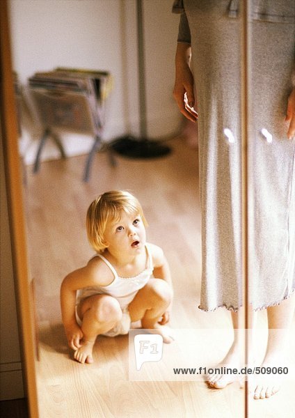 Kind hockt vor dem Spiegel neben der schwangeren Frau