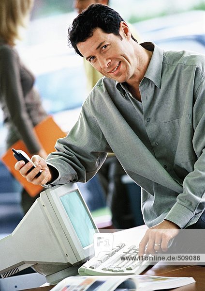 Geschäftsmann auf dem Schreibtisch sitzend mit Handy