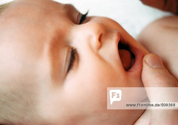 Baby's face with adult finger on chin,  close-up