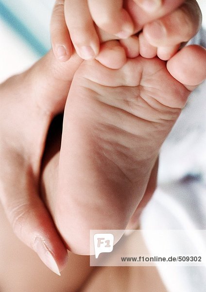 Mutterhand auf Babyfuß  Babyhand hält Mutterfinger  Nahaufnahme