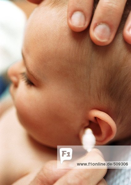 Baby mit Ohrenreinigung mit Wattestäbchen  Nahaufnahme