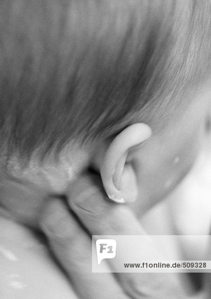 Erwachsene Finger mit Lotion hinter dem Ohr des Babys  Nahaufnahme  s/w