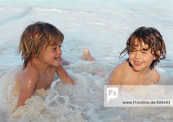 Zwei Mädchen spielen im Wasser und lächeln.