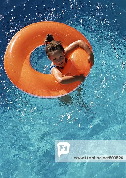 Ein junges Mädchen,  das im Innenrohr im Pool schwimmt,  von oben geschossen.