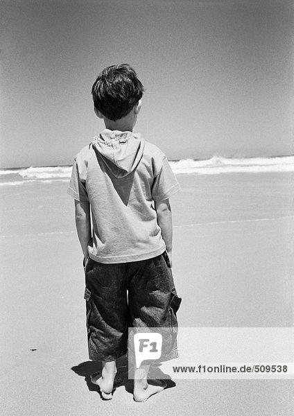 Kleiner Junge am Strand stehend  Rückansicht  Ozean im Hintergrund  B&W