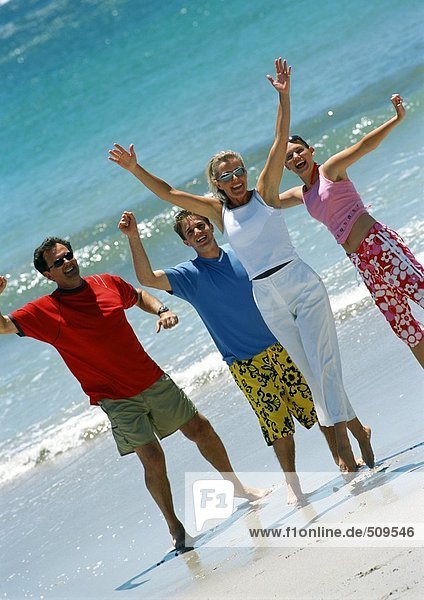 Familie mit zwei Teenagern am Strand  winkend