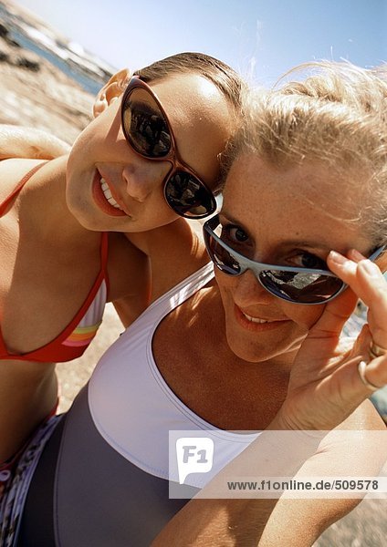 Nahaufnahme von Frau und Mädchen mit Sonnenbrille am Strand.