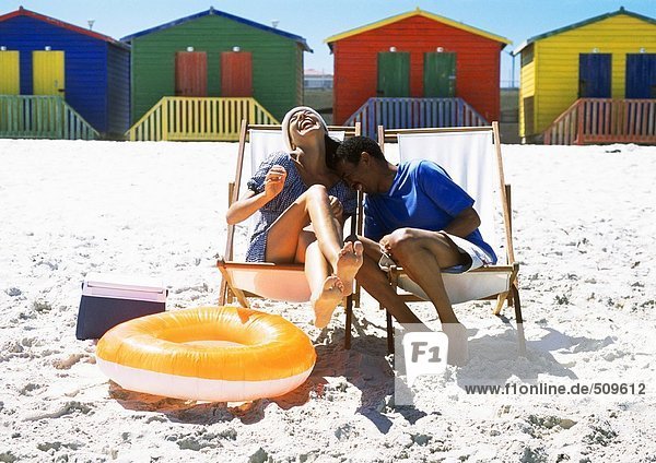 Paar am Strand auf Strandkörben sitzend