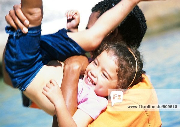 Mann hält Tochter auf der Schulter mit Beinen in der Luft  Mädchen lachend