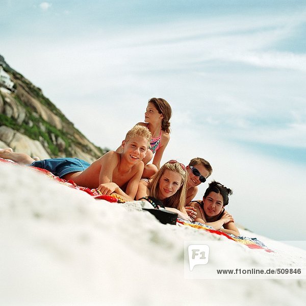 Teenager liegen auf Strandtüchern an der Küste