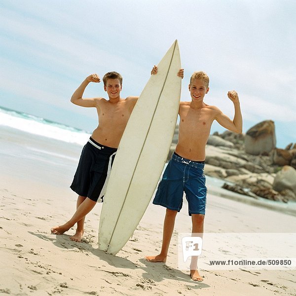 Zwei Jungen am Strand mit Surfbrett