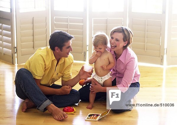 Couple sitting on floor  playing with baby