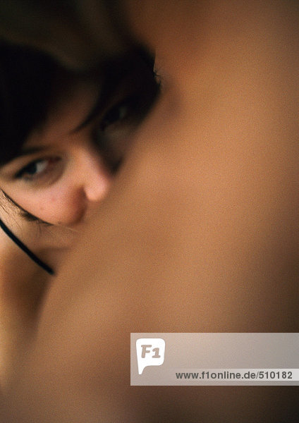 Woman's face behind man's bare shoulder  close-up  focus on face in background