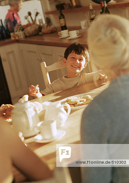 Kind bei Tisch  Großmutter anlächelnd