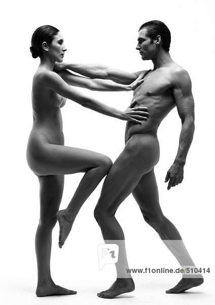 Nude man and woman holding each other at arm's length  woman's knee up  side view  b&w